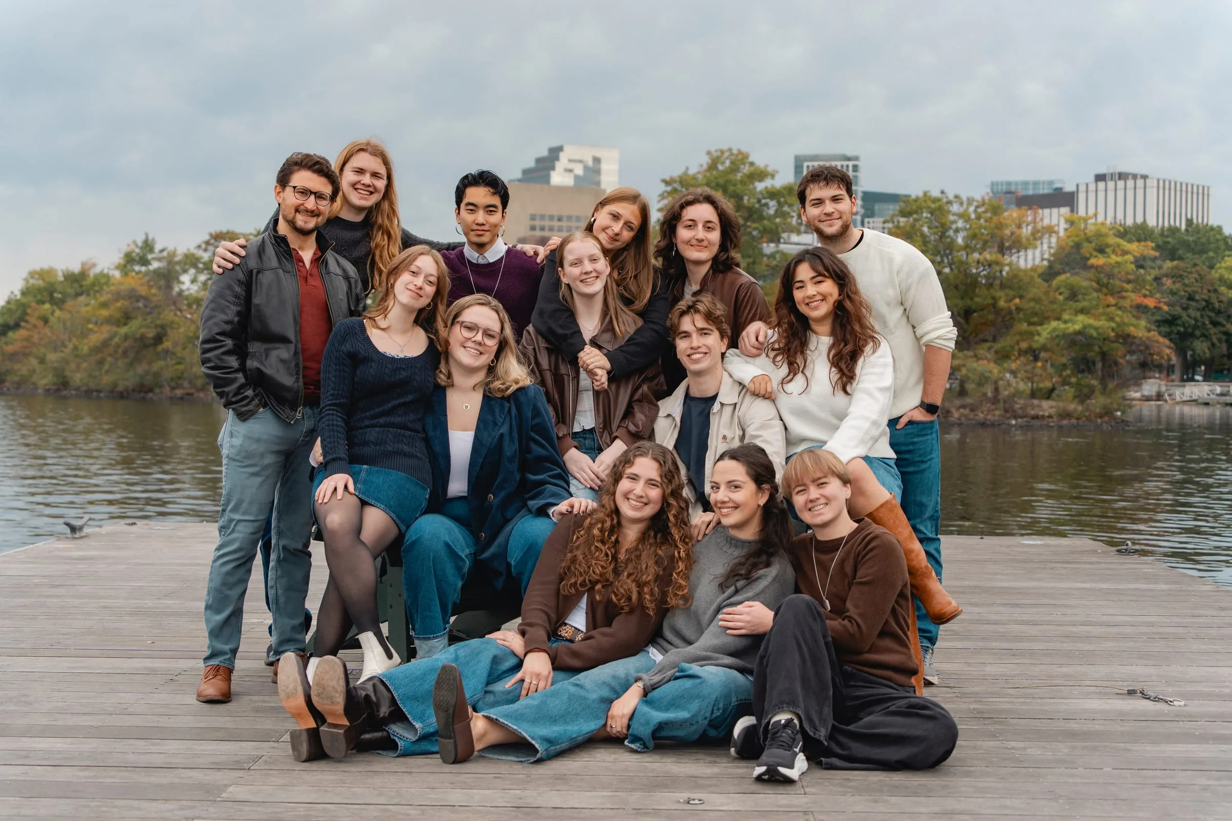 The NU Madrigal Singers posing together on a wooden dock by the river